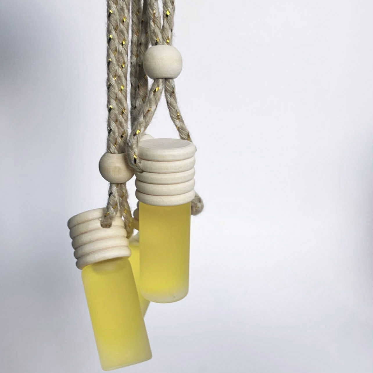 Yellow hanging bottles with white caps on a light gray background