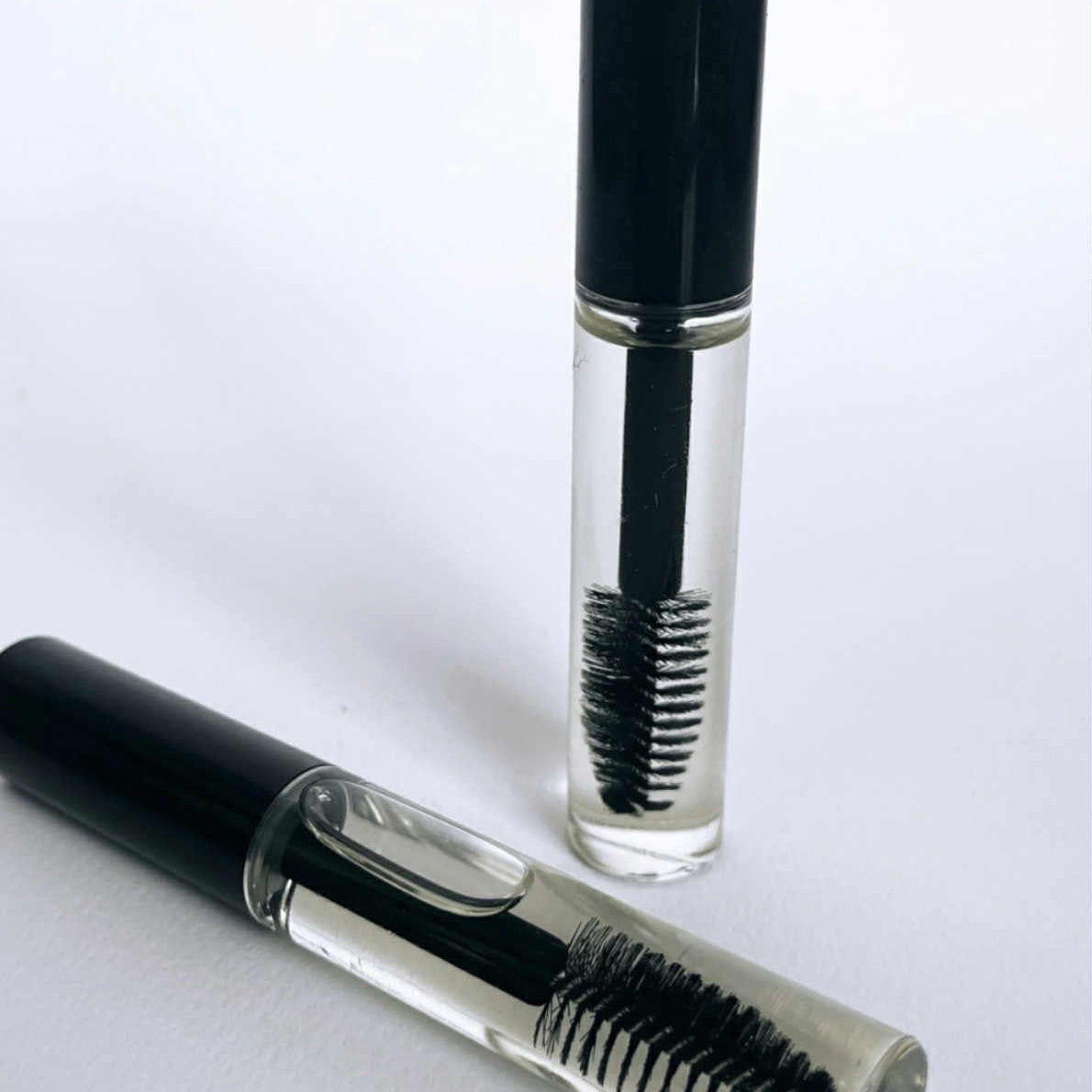 Eyebrow pencil with black brush and clear casing on a white background