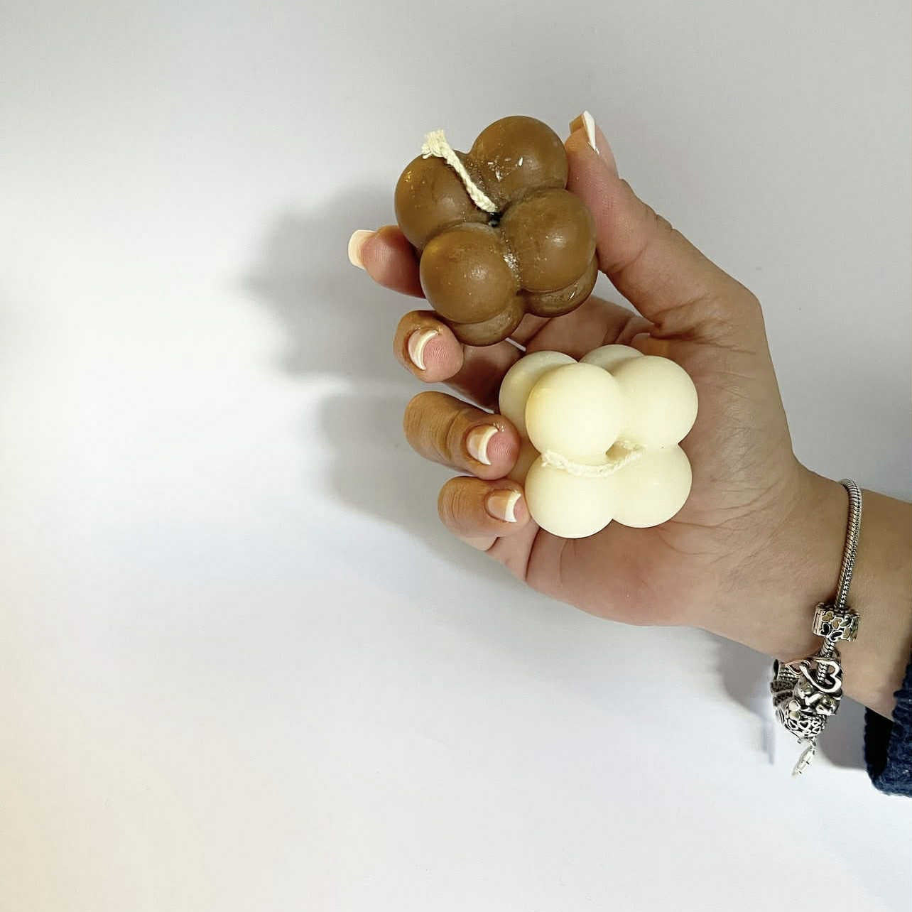 Hand holding two sets of candle-shaped objects against a white background
