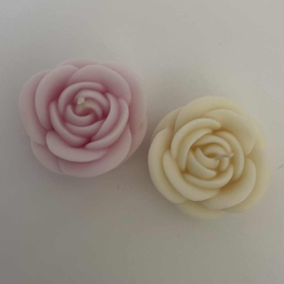 Two floral-shaped candies, one pink and one beige, on a white background.